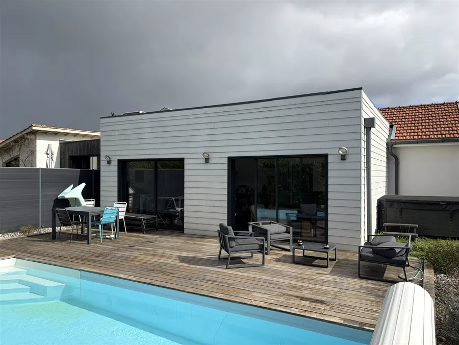 Avant : Terrasse en bois nue équipée d'une pergola bioclimatique anthracite à lames orientables et store latéral, sur la photo réelle du client