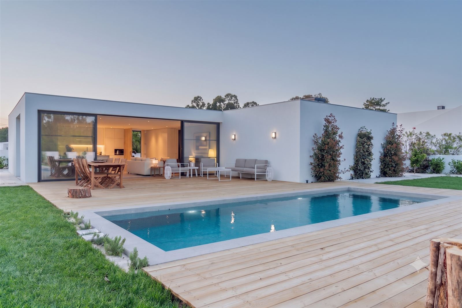 Avant : Terrasse contemporaine transformée par une pergola bioclimatique blanche adossée, avec rideau latéral et éclairage intégré