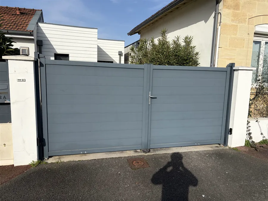 Avant : Portail plein gris remplacé par un modèle ajouré rouge, généré sur la photo réelle du client