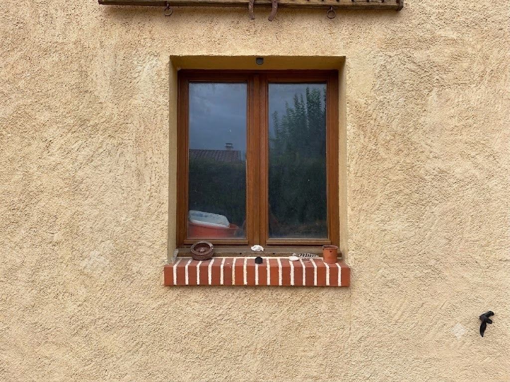 Avant : Menuiserie ancienne d'une maison en pierre équipée de volets battants imitation bois assortis au dormant